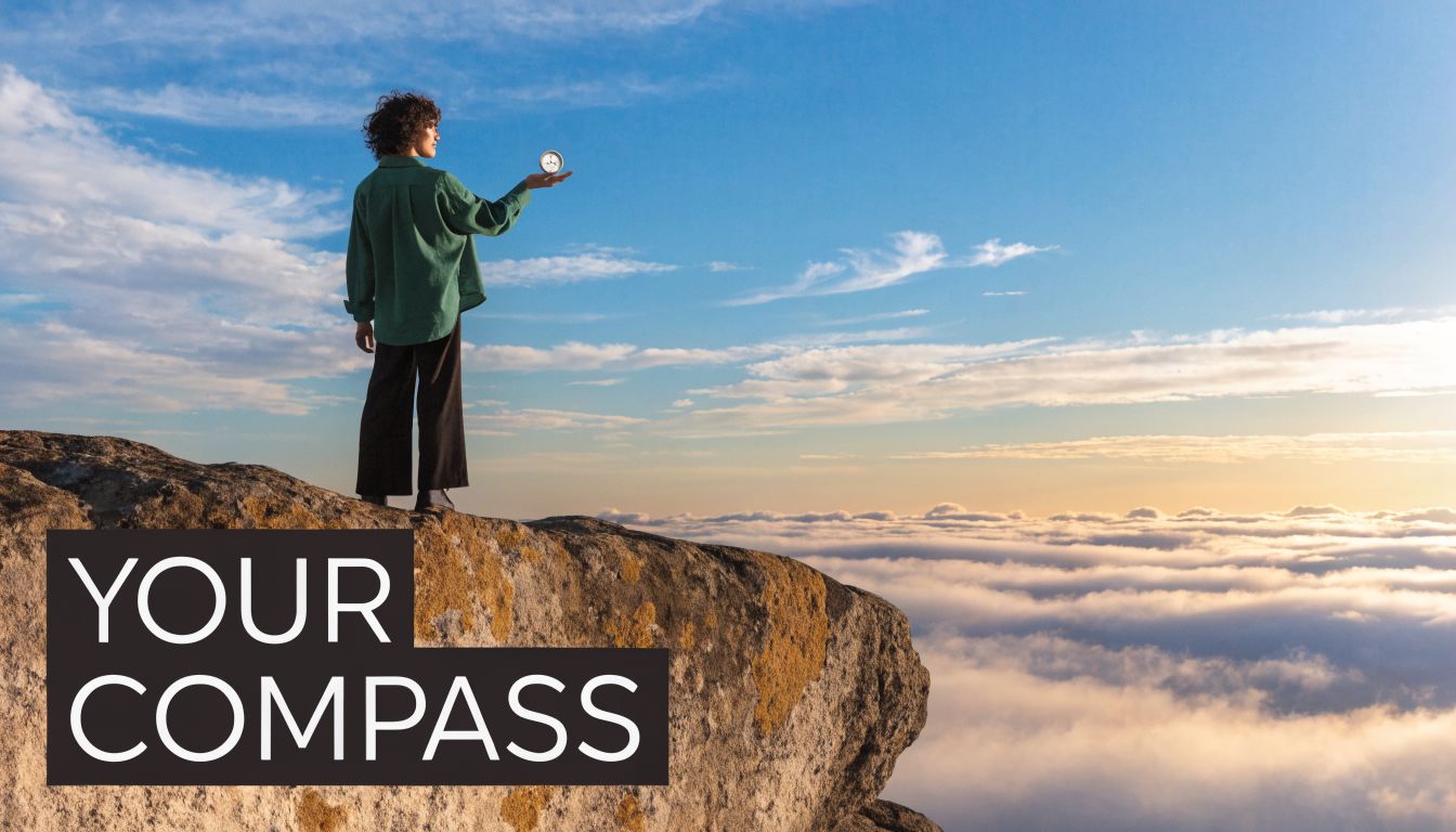 A person standing on a rocky mountain cliff above the clouds, holding a compass in their hand.